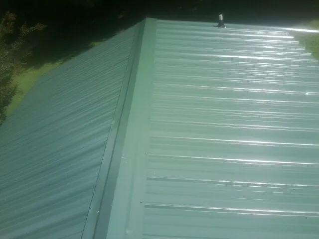 New green metal panels meeting at the ridge of a roof — Flat Roof Repair work by our crew in Hatch