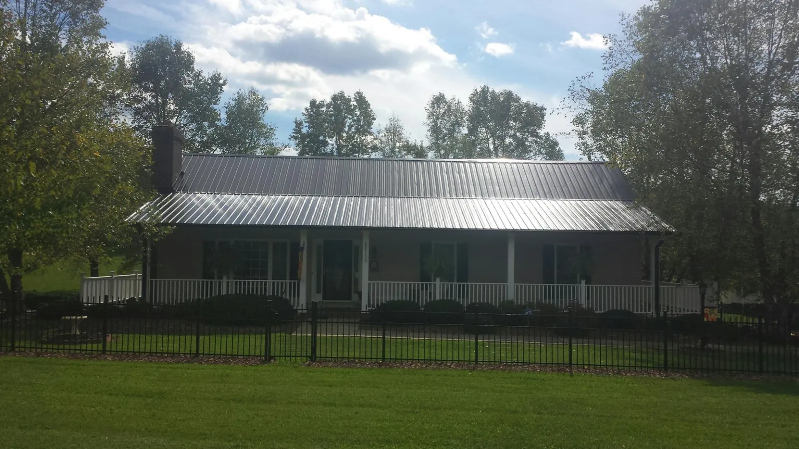 Gray metal roof on a brick ranch with a full width front porch — Gutter Guard Installation work by our crew in Hatch