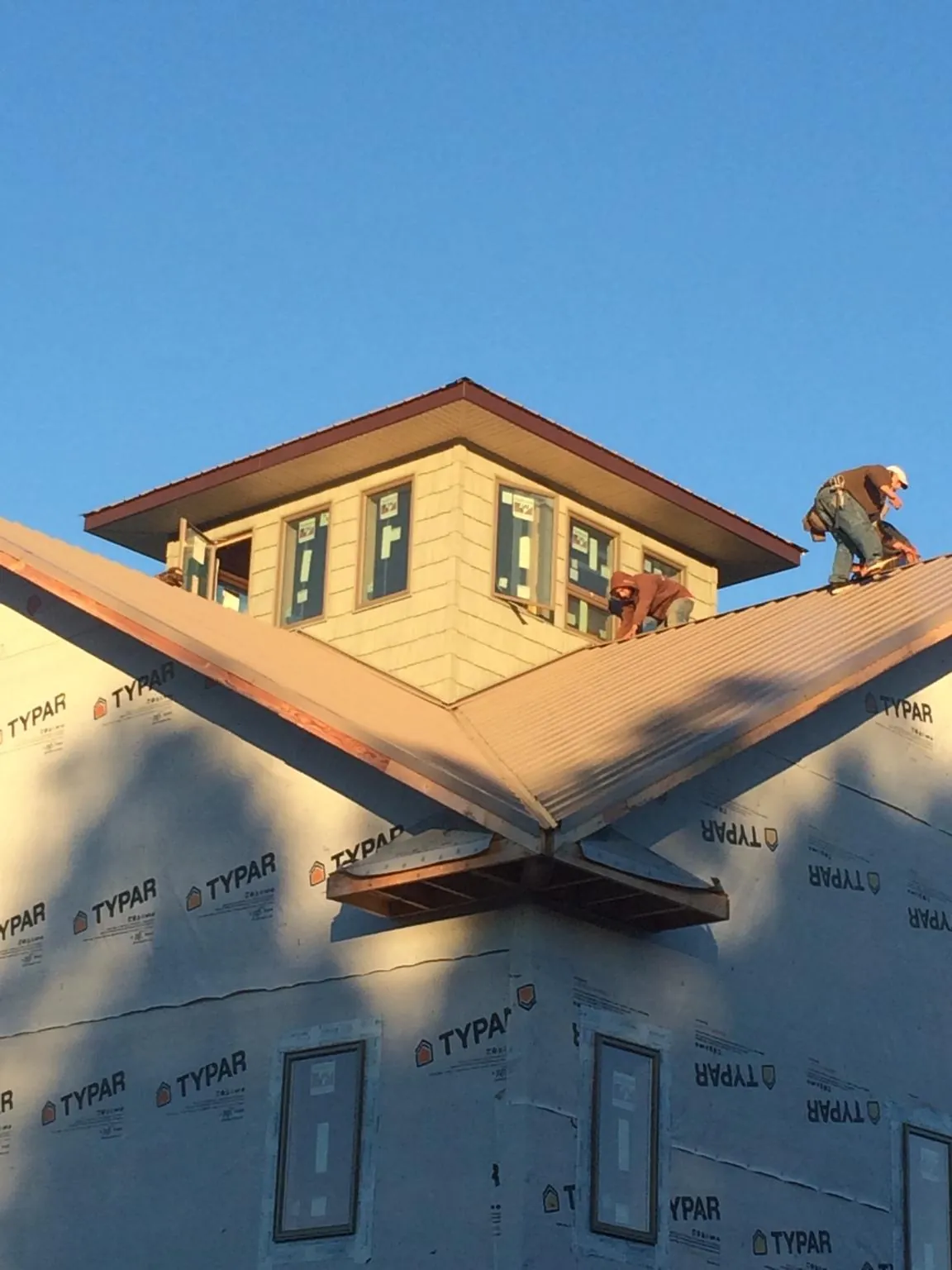 Roofers working around a rooftop cupola on a new metal roof at sunset — Roof Waterproofing in Hatch by Roofing Brothers
